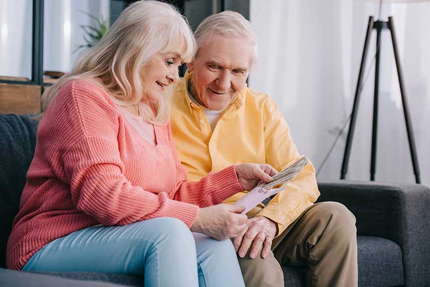 Happy senior couple holding envelope with money
