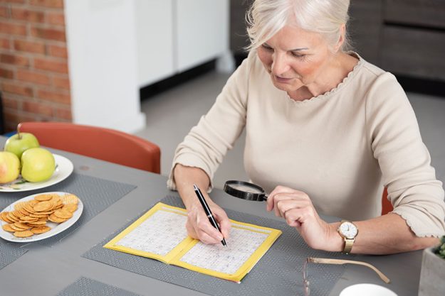 Senior woman enjoys solving a crossword puzzle