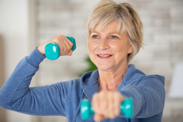 cheerful senior lady exercising with weights Enjoying An Active Retirement In Your Independent Living Apartment: 7 Tips To Fight Fatigue