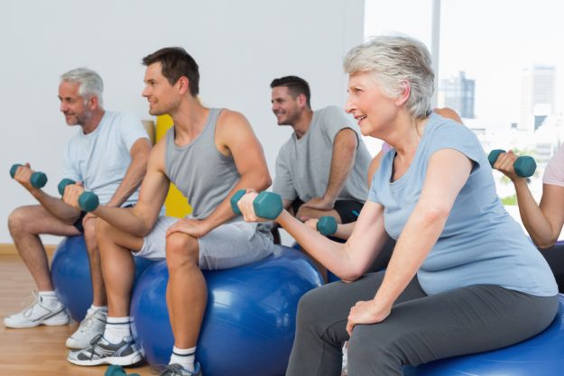 Side view of fitness class with dumbbells sitting on exercise balls in a bright gym How Independent Living In Spring, TX Prepares Safe Activities For Seniors With Limited Mobility