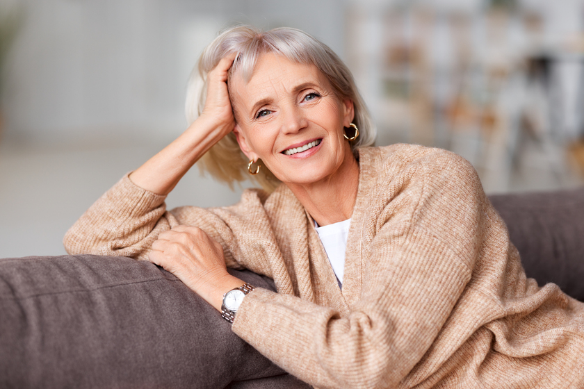 elderly beautiful woman smiles at camera while sitting on the sofa at home How Senior Living In Bisbee, TX Provides A Peaceful Environment For Residents