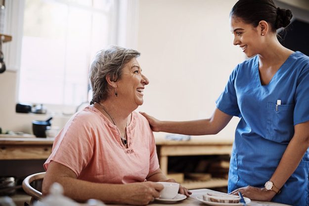 an attractive young female caregiver with a senior patient in a nursing home an attractive young female caregiver with a senior patient in a nursing home