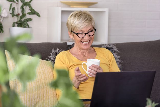 Beautiful senior elderly woman at home using laptop