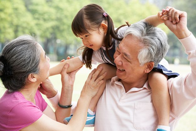 Chinese Grandparents Giving Granddaughter Ride On Shoulders