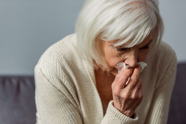 Depressed senior woman crying while holding paper napkin Depressed senior woman crying while holding paper napkin