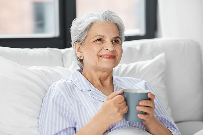 Old woman with cup of coffee in bed at home Old woman with cup of coffee in bed at home