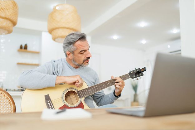 Senior Adult Man practicing to play acoustic guitar