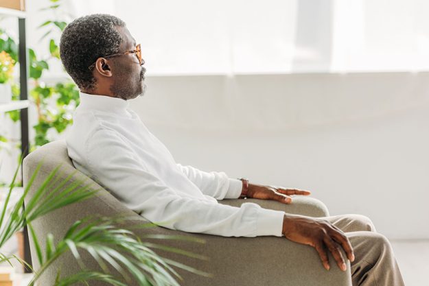 Stylish African American man sitting in armchair and looking away Stylish African American man sitting in armchair and looking away