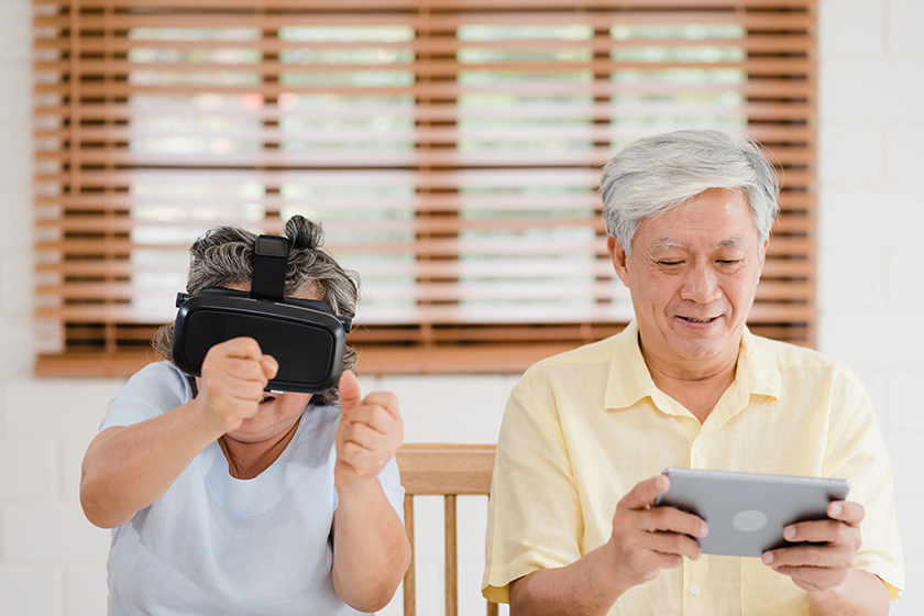 asian elderly couple using tablet and virtual reality simulator
