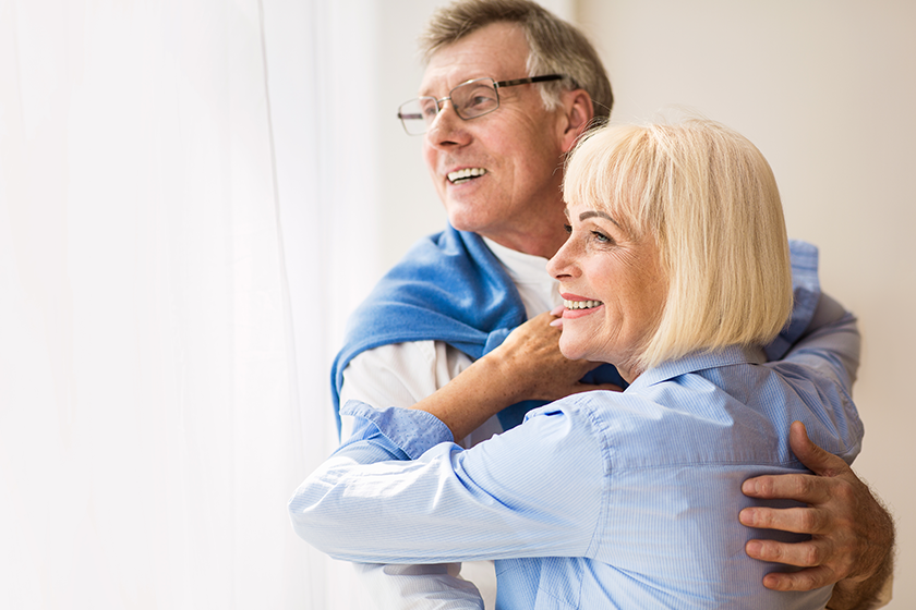 Mature couple hugging and looking through window Mature couple hugging and looking through window