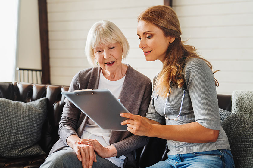Senior old woman sits with middle aged nurse