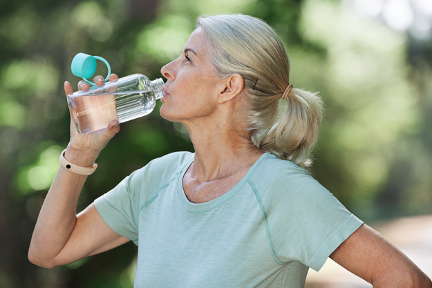 shot mature woman drinking water while exercising