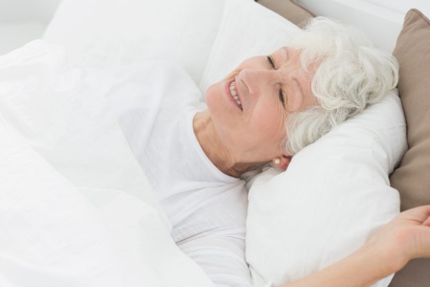 Smiling old woman sleeping on the bed Aging In Nursing Homes In Victoria Texas: Tips For Getting Restful Sleep