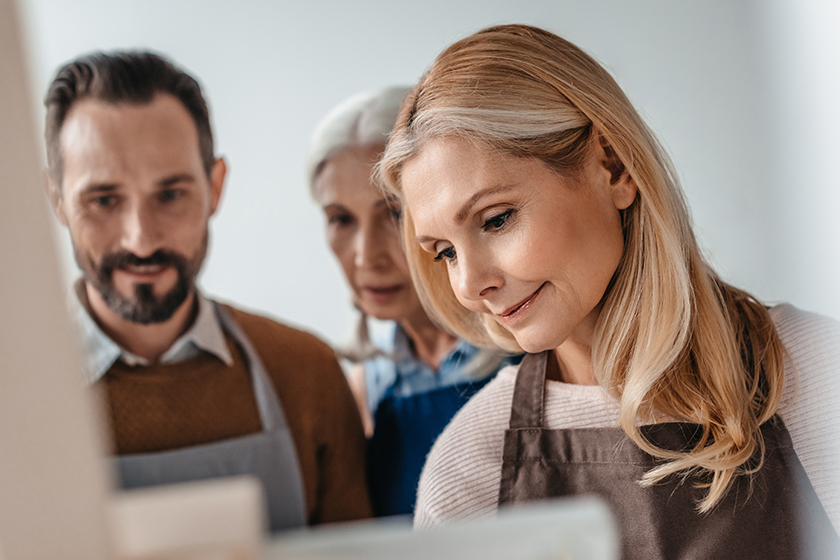 Beautiful mature woman painting on easel during art class for adults