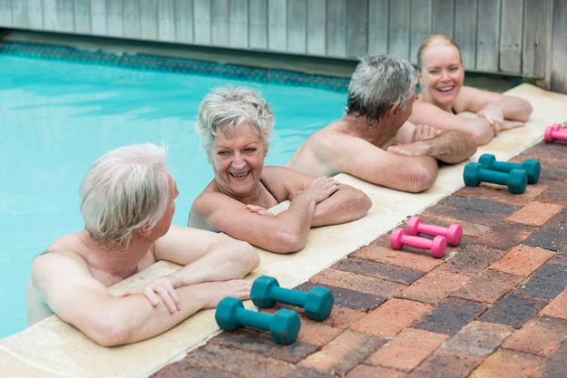 Cheerful swimmers leaning on poolside