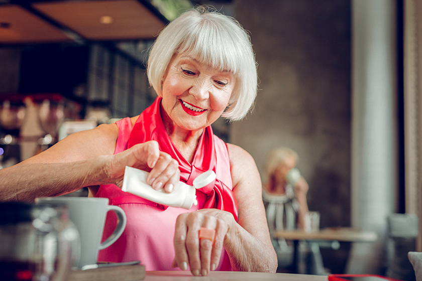 Joyful nice woman putting cream on her hand