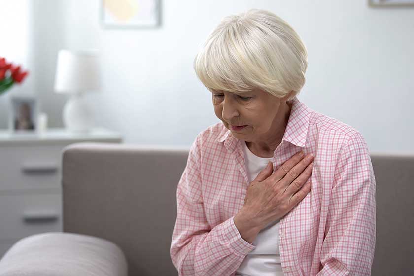 Old woman with heart disease holding hand on chest
