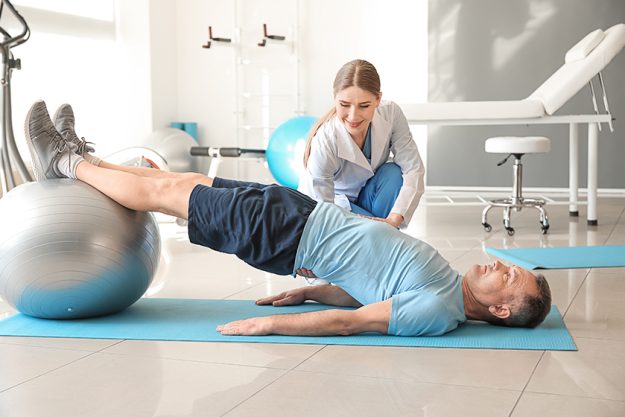 Physiotherapist working with mature patien