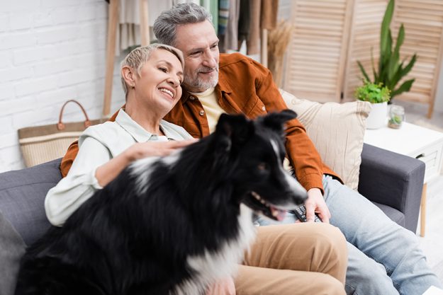 Positive senior woman petting blurred border collie dog