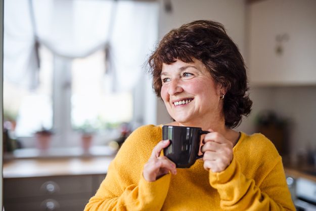 Senior woman with cup of coffee at home