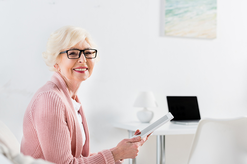 Side view of smiling senior woman with tablet