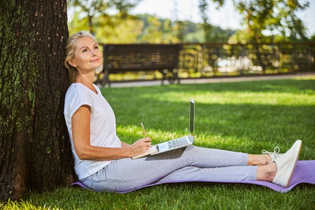 Beautiful woman sitting on green grass in park
