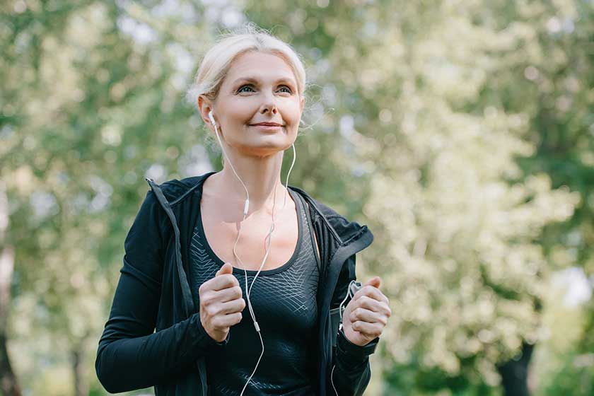 beautiful mature sportswoman looking away while running park listening music beautiful mature sportswoman looking away while running park listening music