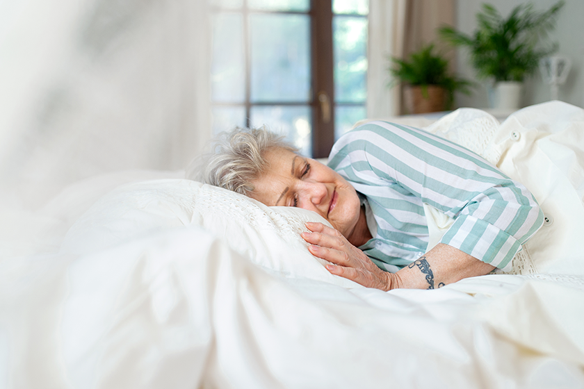 Happy senior woman in bed at home