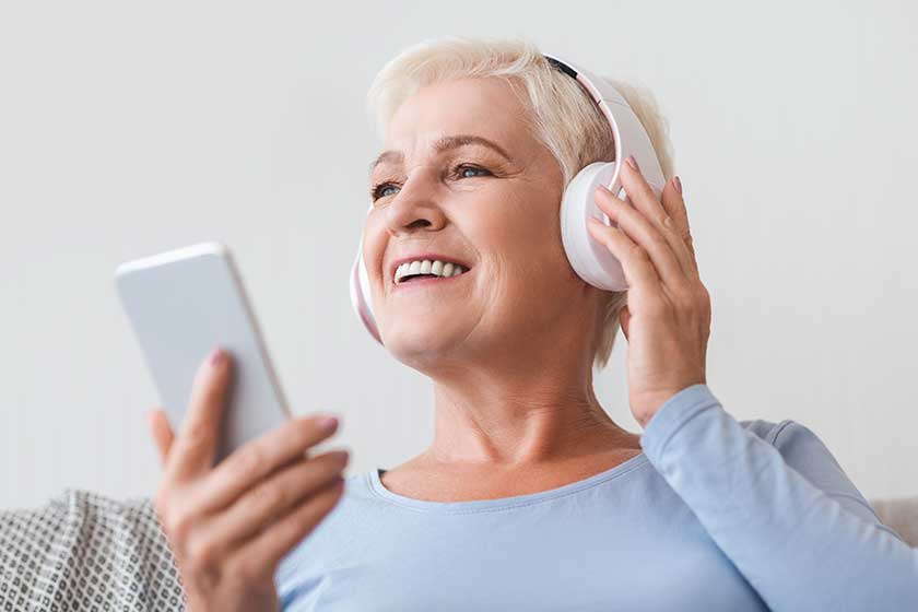 Senior woman enjoying music and watching videos on smartphone