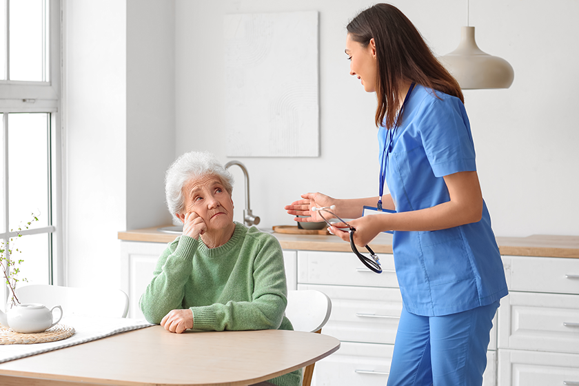 Young caregiver with senior woman in kitchen