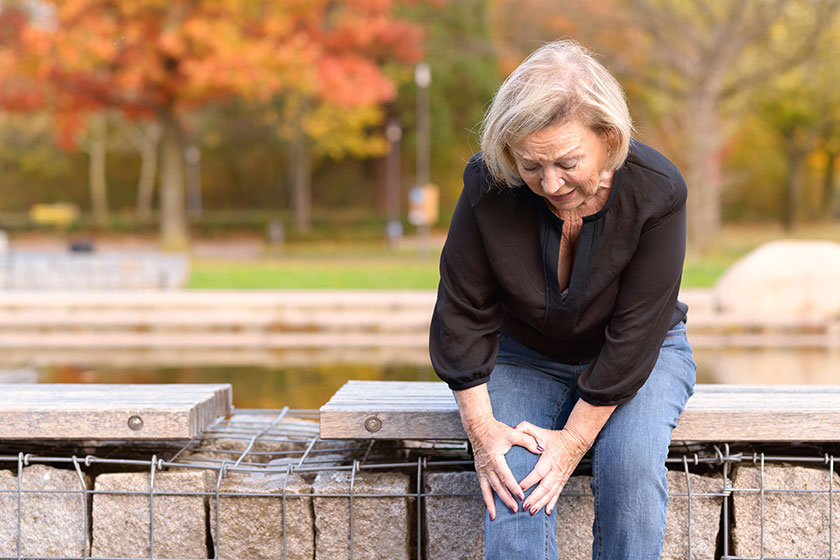 Elderly lady grabbing her knee in pain Elderly lady grabbing her knee in pain