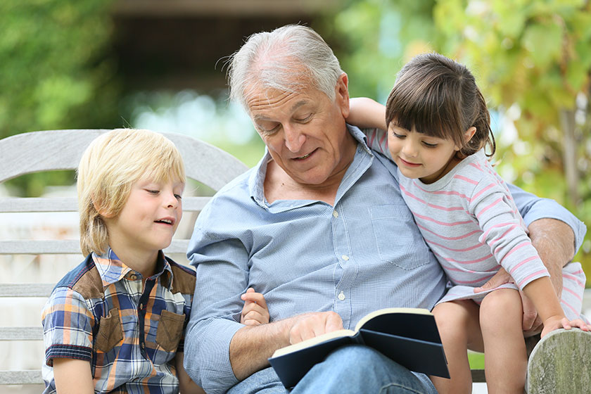 man reading book with grandkids