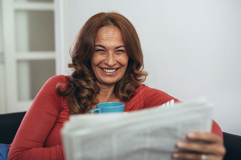 mature woman drinking coffee tea reading newspapers her home