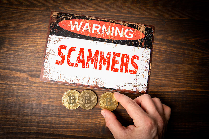 SCAMMERS. Warning sign and bitcoin coins on wooden taxture table