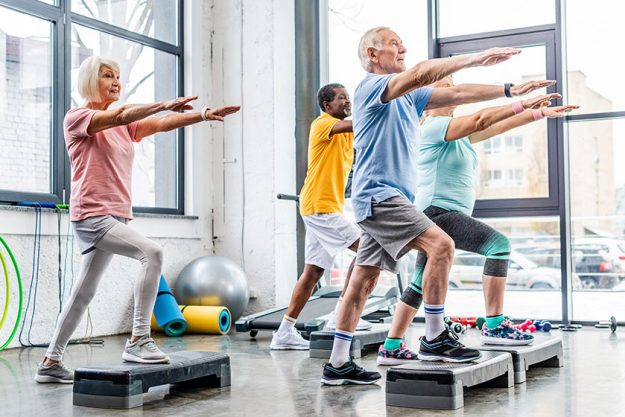 Senior athletes synchronous exercising step platforms gym