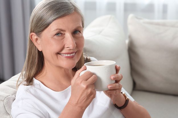 Senior woman with cup of tea on sofa at home Senior woman with cup of tea on sofa at home
