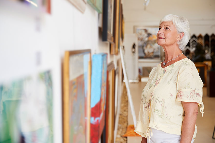 senior woman looking paintings art gallery