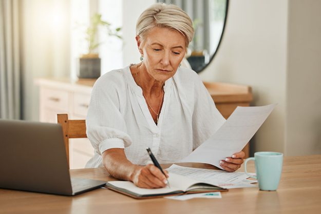 senior woman notebook writing budget plan retirement review finance documents