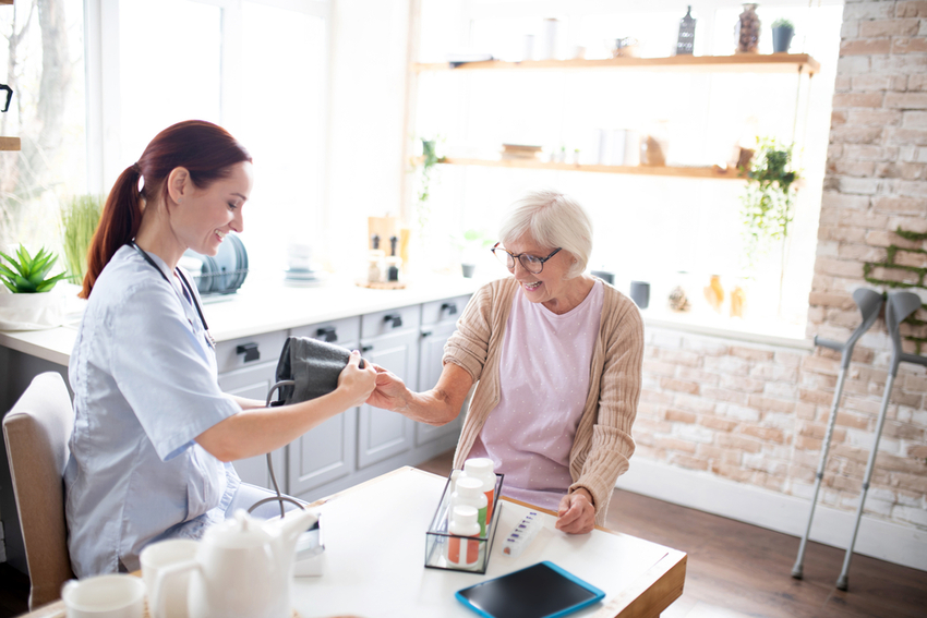 Nurse measuring blood pressure for retired lady