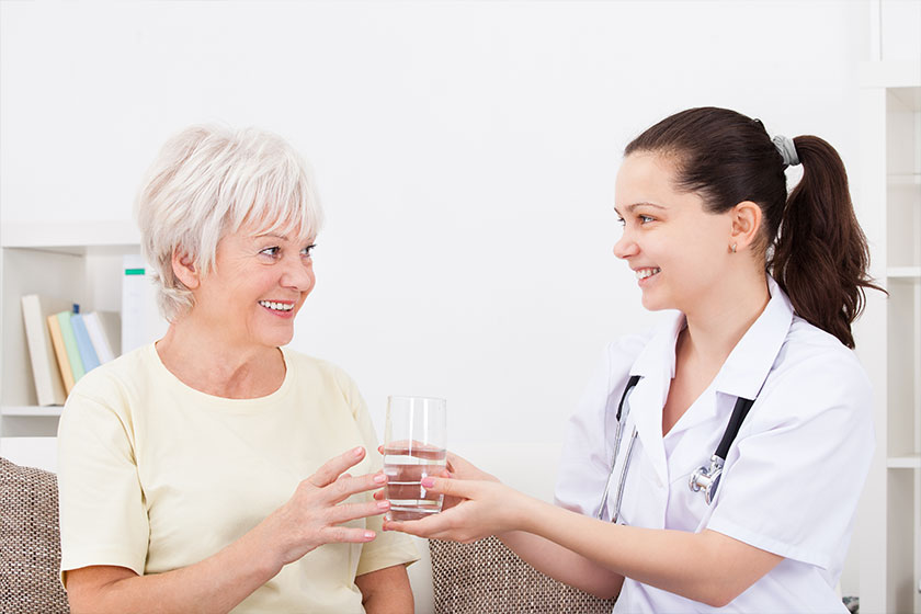 Young doctor with patient holding glass