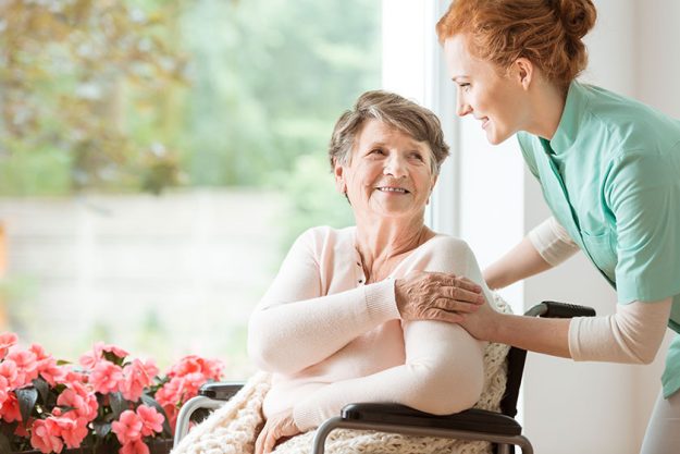 Young nurse helping an elderly woman in a wheelchair nursing home concept Young nurse helping an elderly woman in a wheelchair nursing home concept