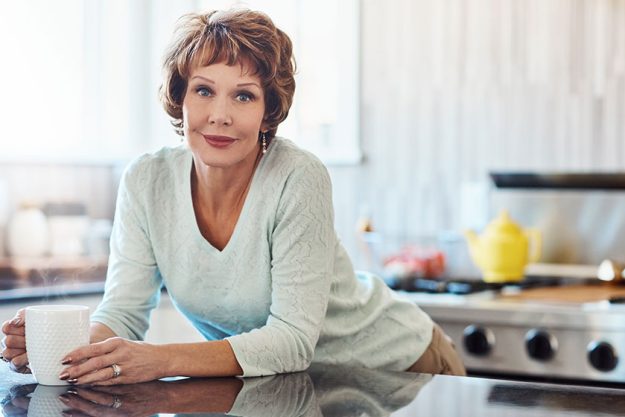 All well home mature woman enjoying warm beverage kitchen home