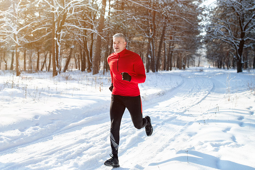 Athletic mature man in sportswear jogging at snowy winter park healthy senior runner sprinting outdoors Athletic mature man in sportswear jogging at snowy winter park healthy senior runner sprinting outdoors