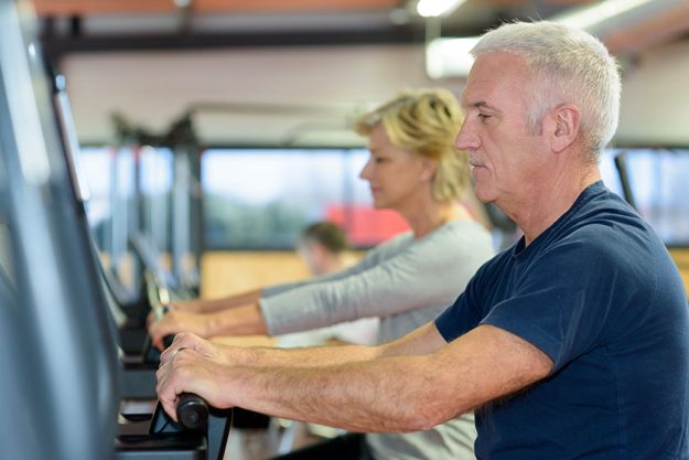 Beautiful fit senior couple gym doing cardio work out Beautiful fit senior couple gym doing cardio work out