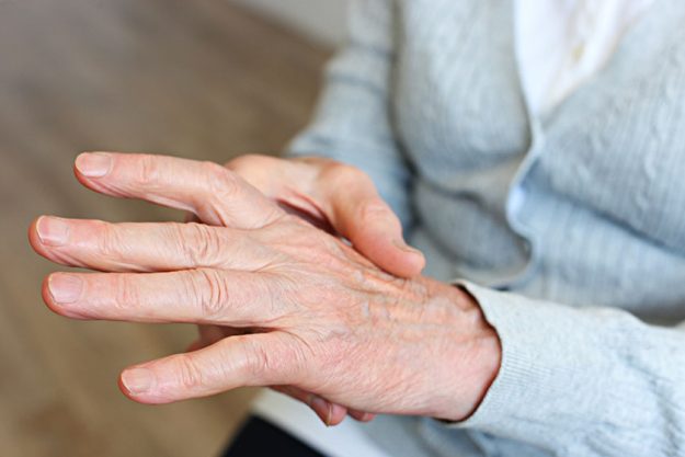 Close up shot of elderly womans hands old lady wearing grey knitted cardigan
