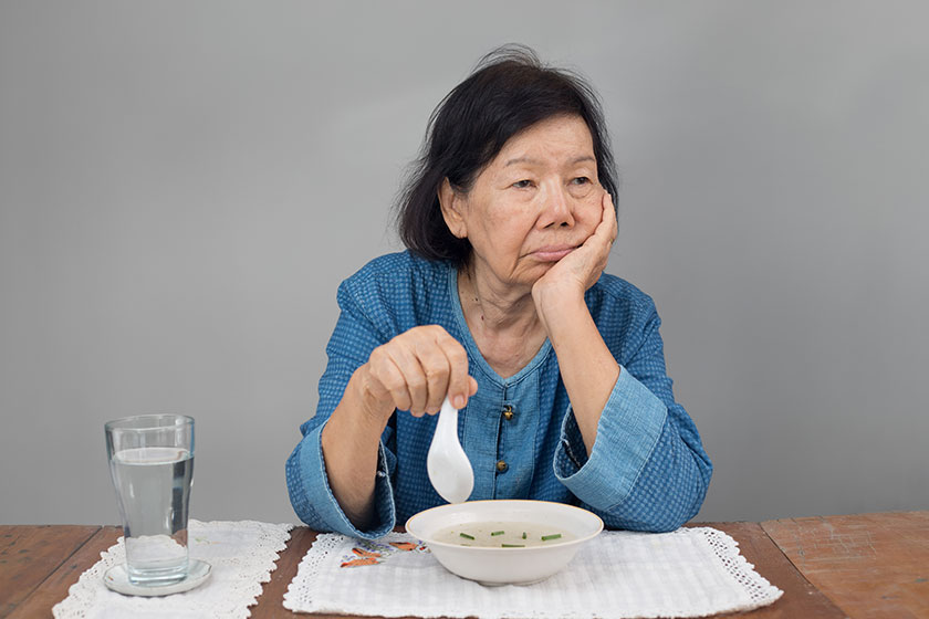 Elderly asian woman bored with food
