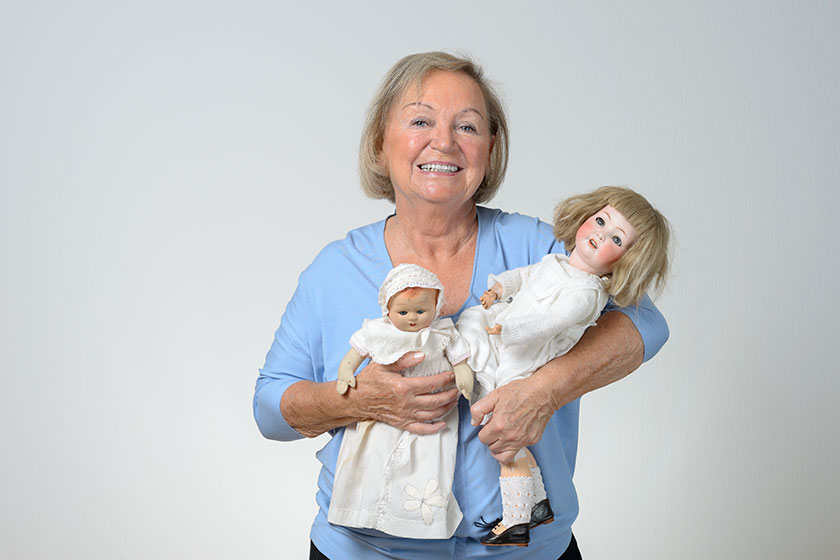 Elderly woman holding two antique dolls