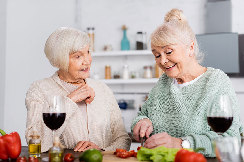 Happy senior woman cutting vegetables