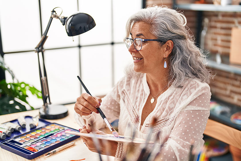 Middle age woman artist holding paintbrush palette art studio Middle age woman artist holding paintbrush palette art studio