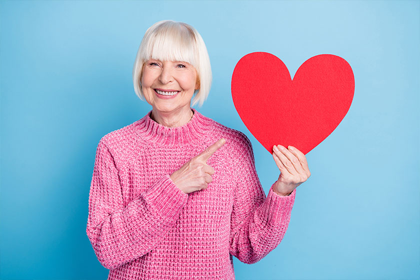 Photo portrait of old woman pointing finger at holding heart card Photo portrait of old woman pointing finger at holding heart card